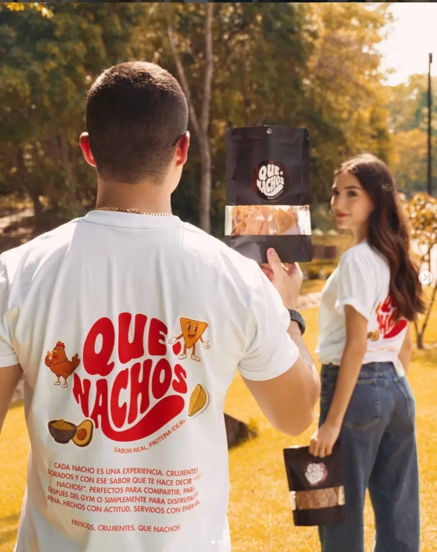 Pareja en el parque con polera y bolsa de Que Nachos